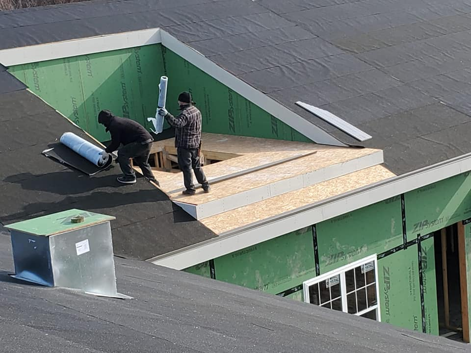 roofing project in progress, roofers working on sloped roof installing underlayment